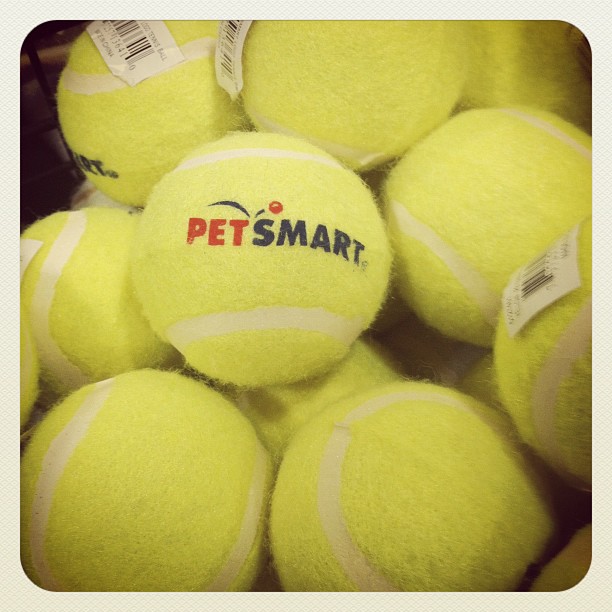 a pile of yellow tennis balls stacked together with the words pet smart on them