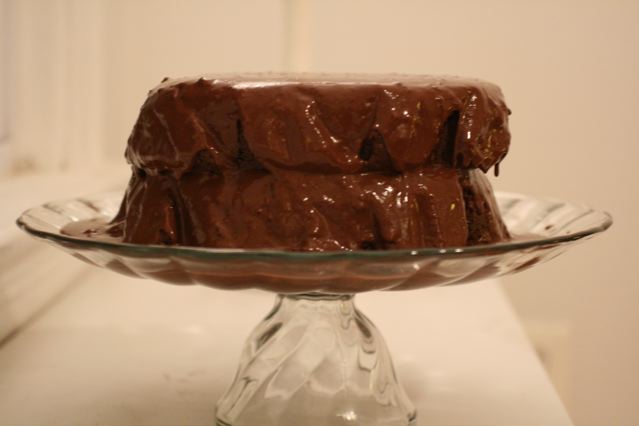 a glass cake stand with a frosted chocolate cake