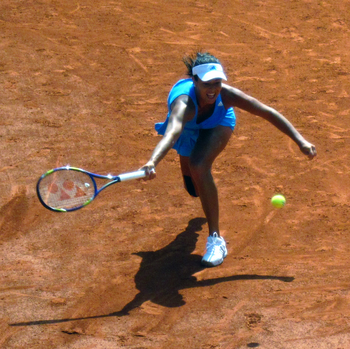a woman in a blue top a tennis court and a ball