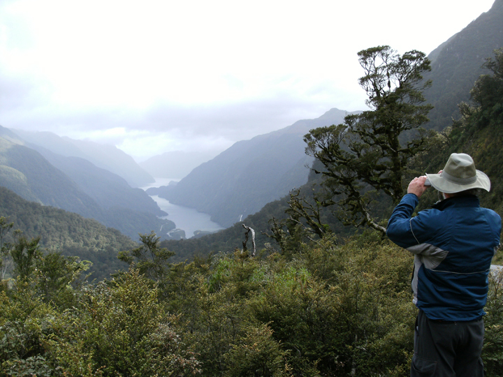 man overlooking scenic view of a mountain, river and forest