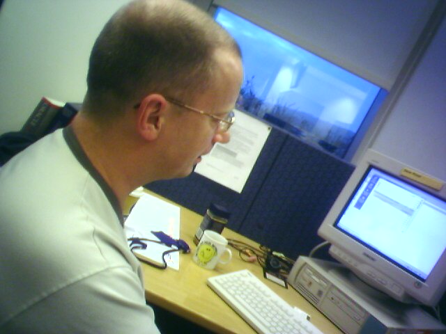 a man with glasses looking at a computer monitor