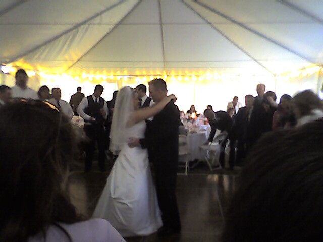 a bride and groom kiss underneath a tent set up for the reception