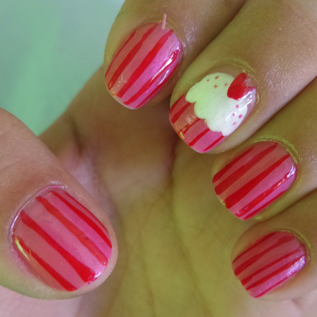 a person with red and white stripes has a white heart on her nails
