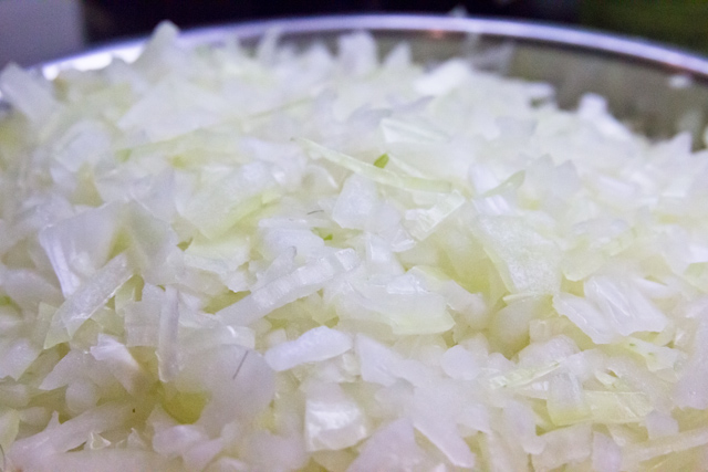 the chopped white onions are in a metal bowl