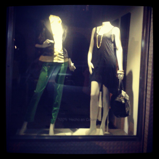 two mannequins and a purse are in a window display