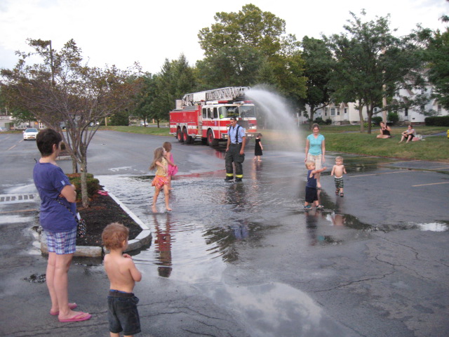 children playing in water at a fire truck opening