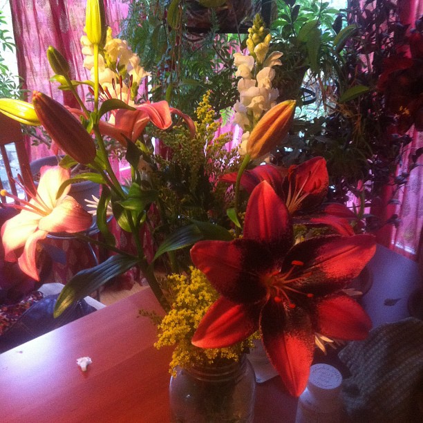 a vase filled with red lilies on top of a wooden table