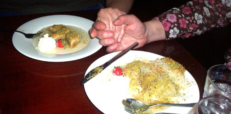 two people sitting at a table holding hands over their dinner