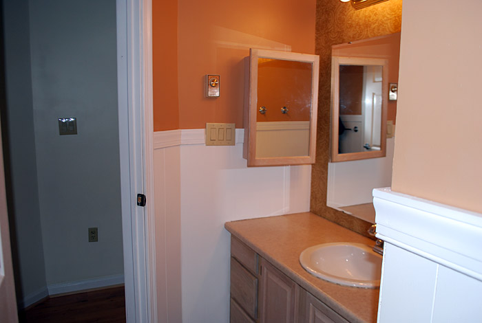 an orange bathroom with a sink and medicine cabinet