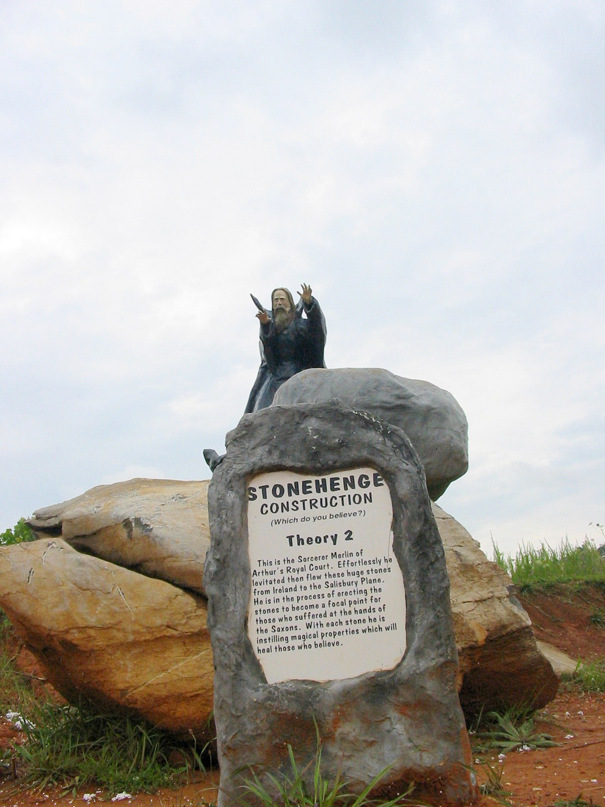 a statue sitting on top of a rock with a plaque in front of it