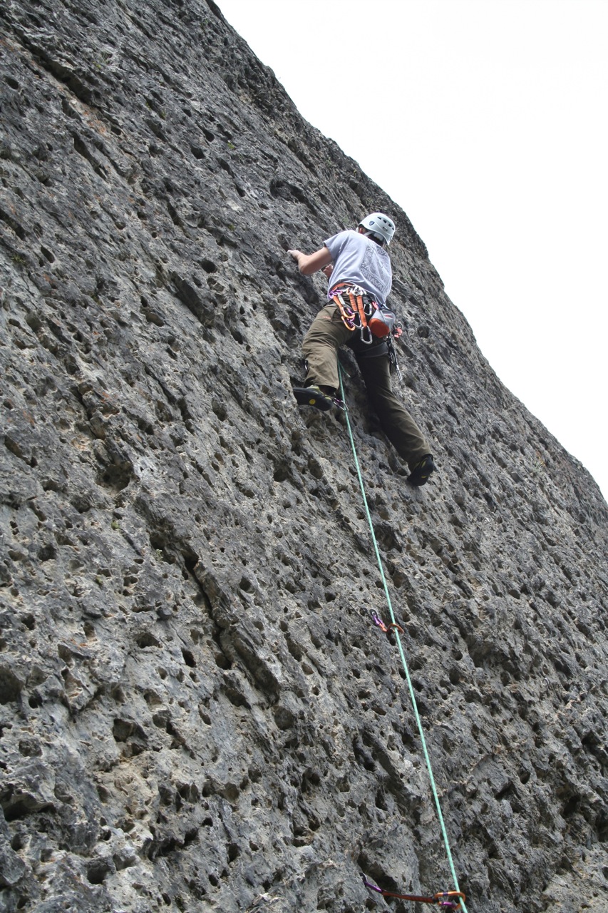 a person with helmet climbing on a rock wall