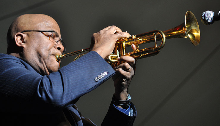 a man wearing glasses playing on a trumpet