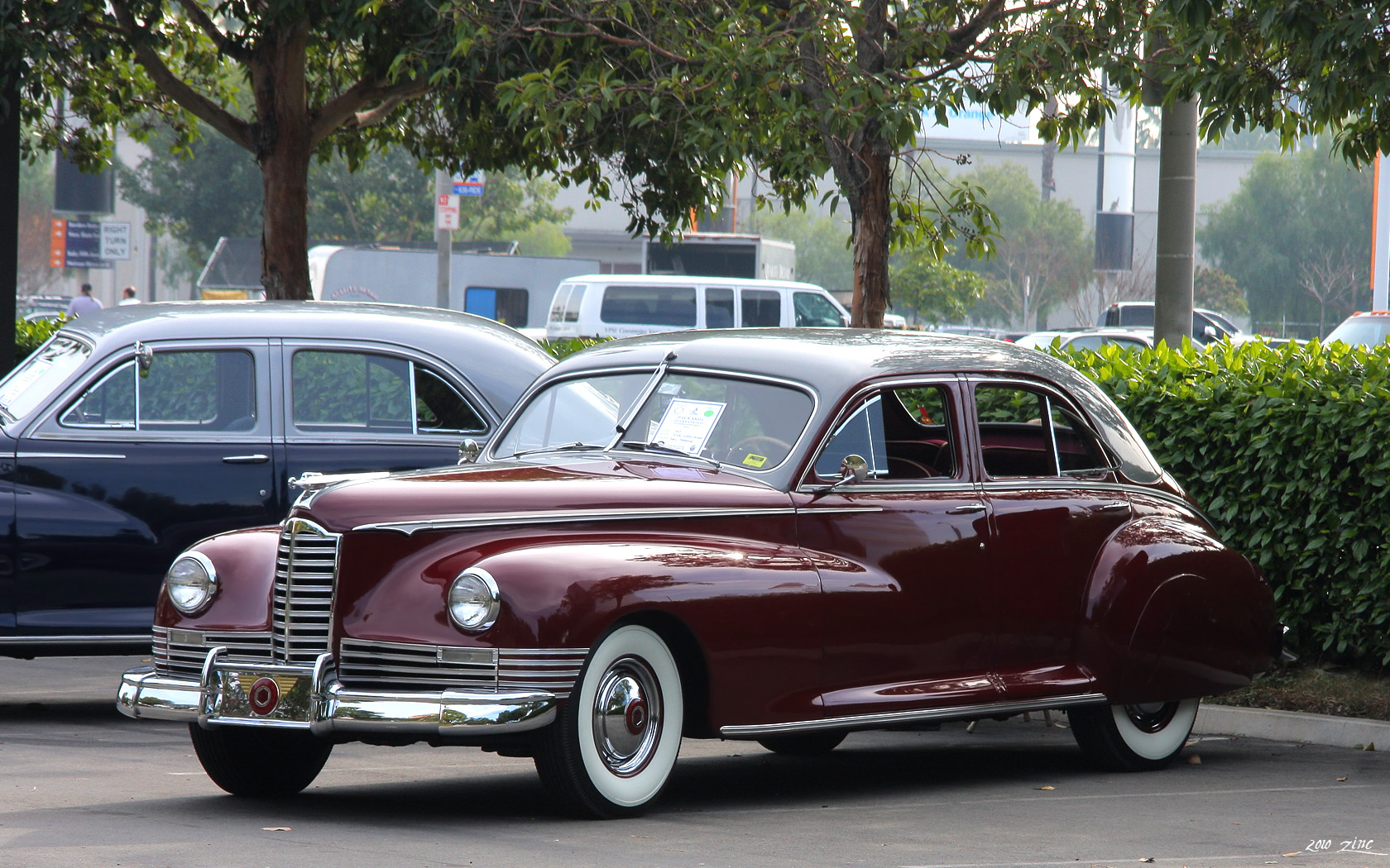 an old burgundy car is parked by some trees