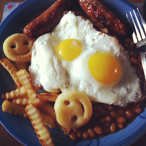 a blue plate topped with eggs, sausage and beans
