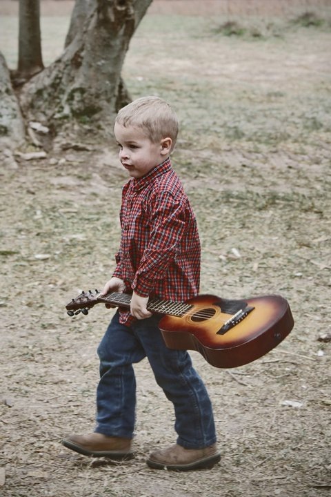 a little boy with a guitar on the field