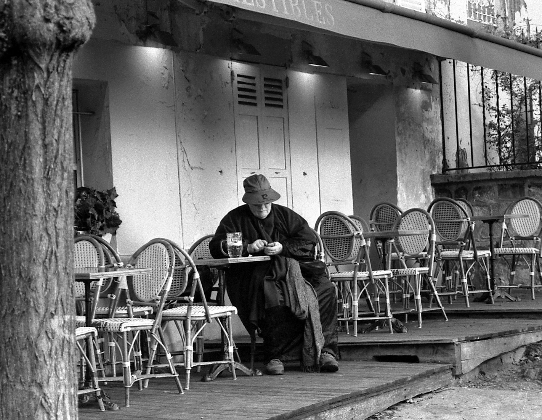 black and white pograph of a man sitting in front of a building