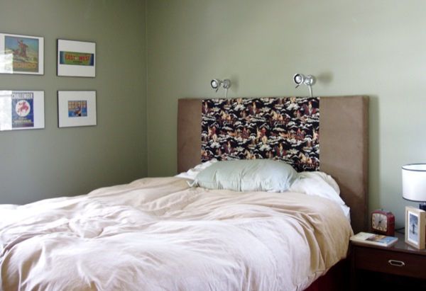 bed with pillows in corner next to night stand and framed pictures