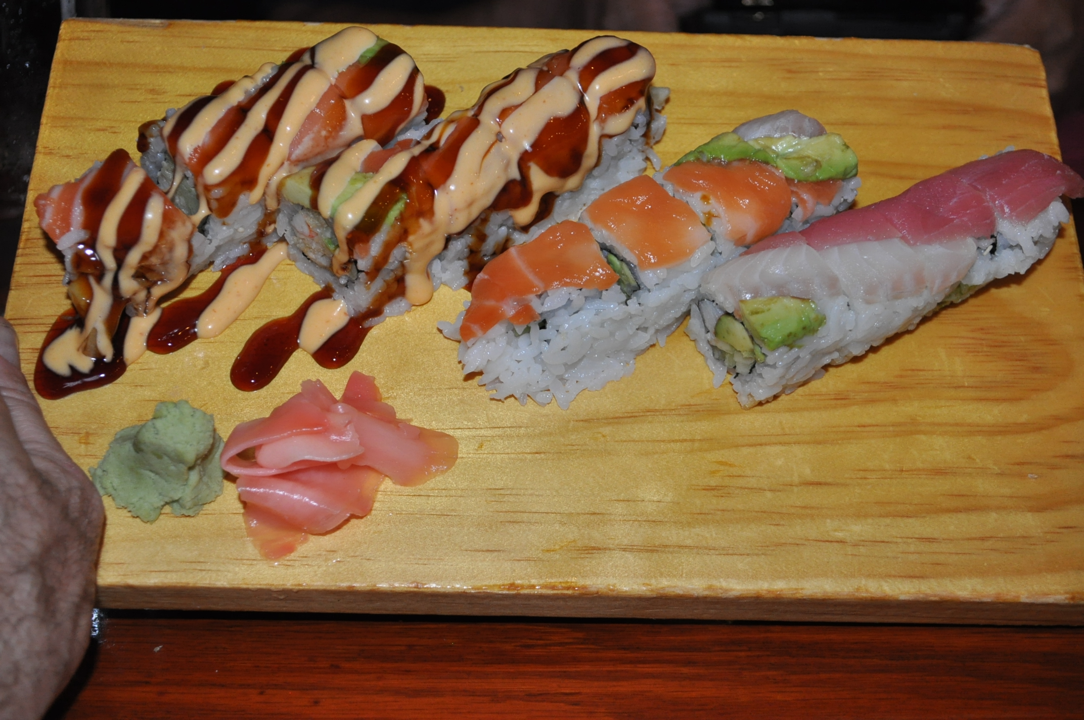 three pieces of sushi on wooden tray with sauce on top