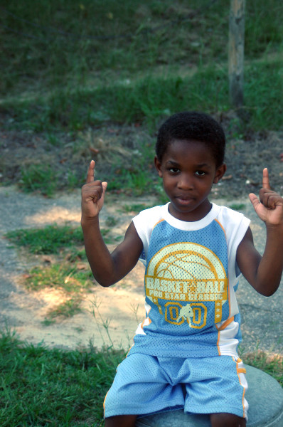 a little boy is sitting down with his peace signs