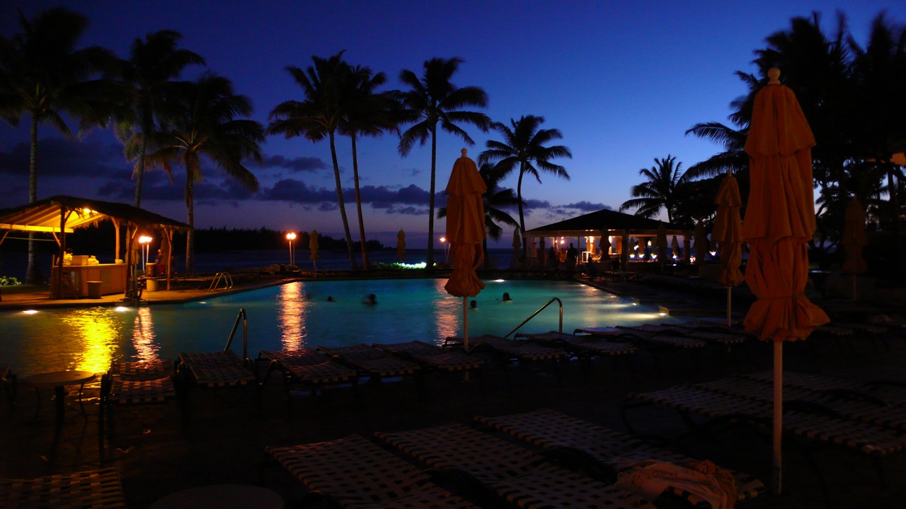 a nighttime view of an outdoor resort pool