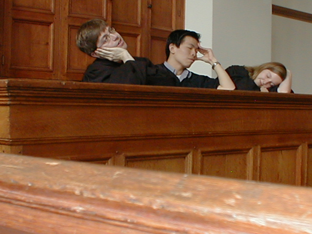 three people sitting in a courtroom looking at soing