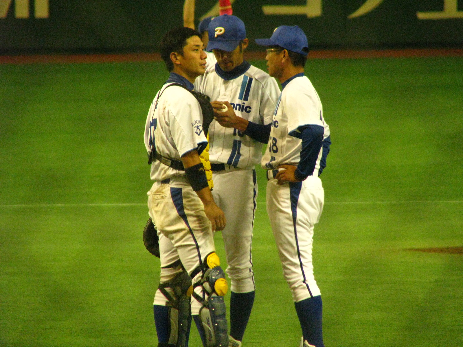 three baseball players are having a conversation at the base