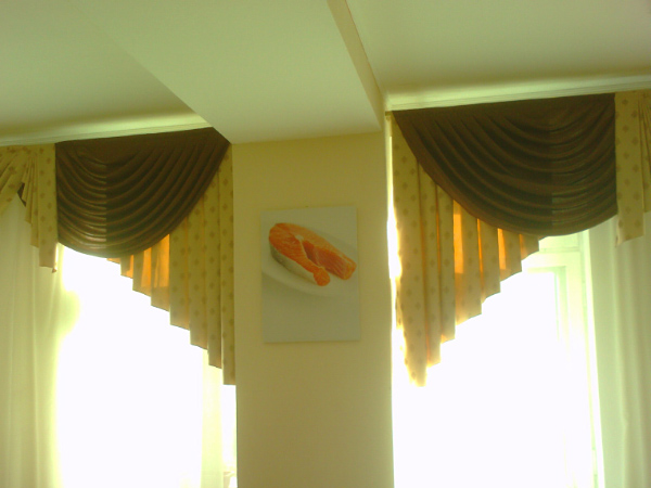 there are two windows with curtain's, one behind a window with sheer valances