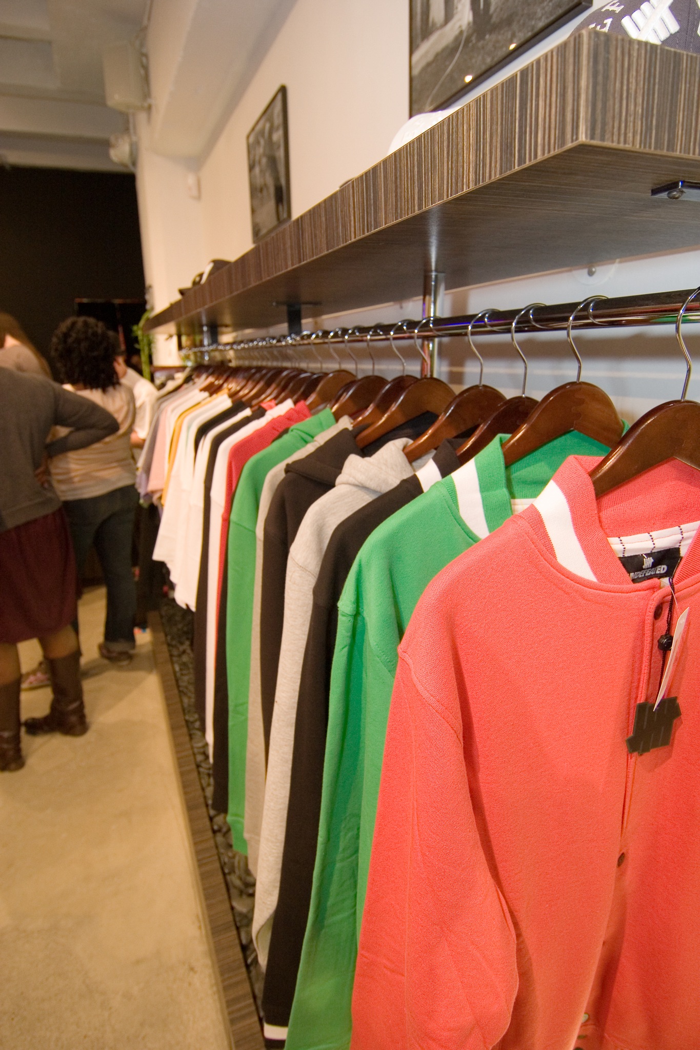 clothes on racks on the wall with people in the background