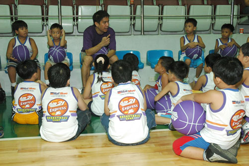 a group of children sitting on the floor in front of basketball players