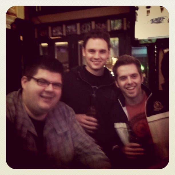 three guys posing for a picture while holding drinks