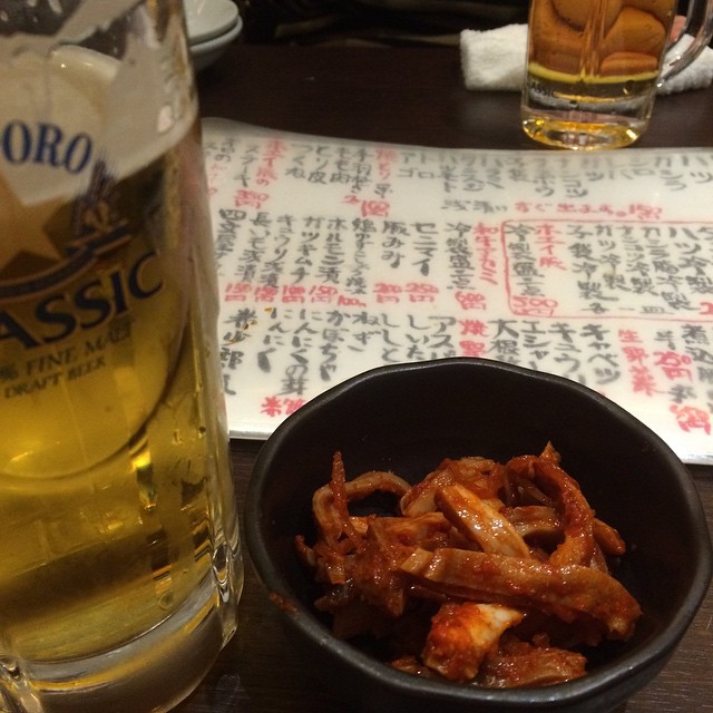 a bowl of fried food next to a tall glass of beer