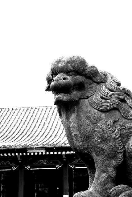 a stone statue in front of a building with an asian - style roof