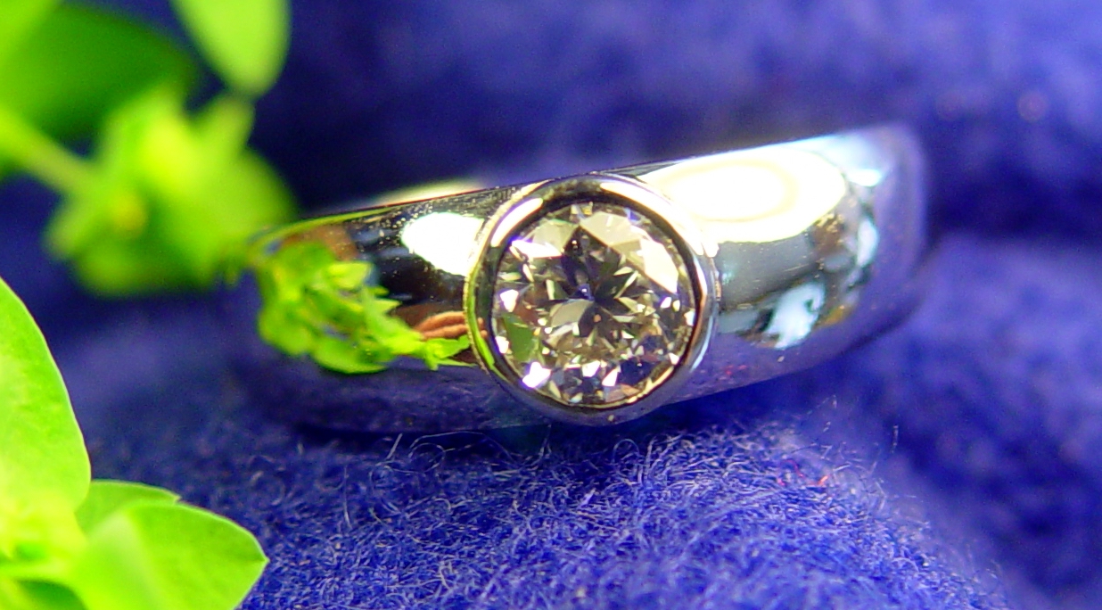 a close up view of a ring with flowers behind it