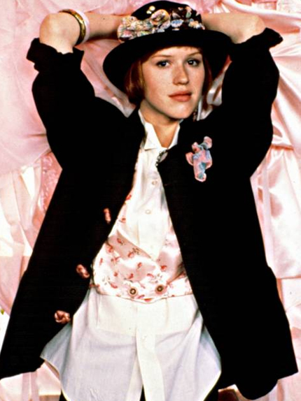 young woman with a coat, vest and flowered hat posing