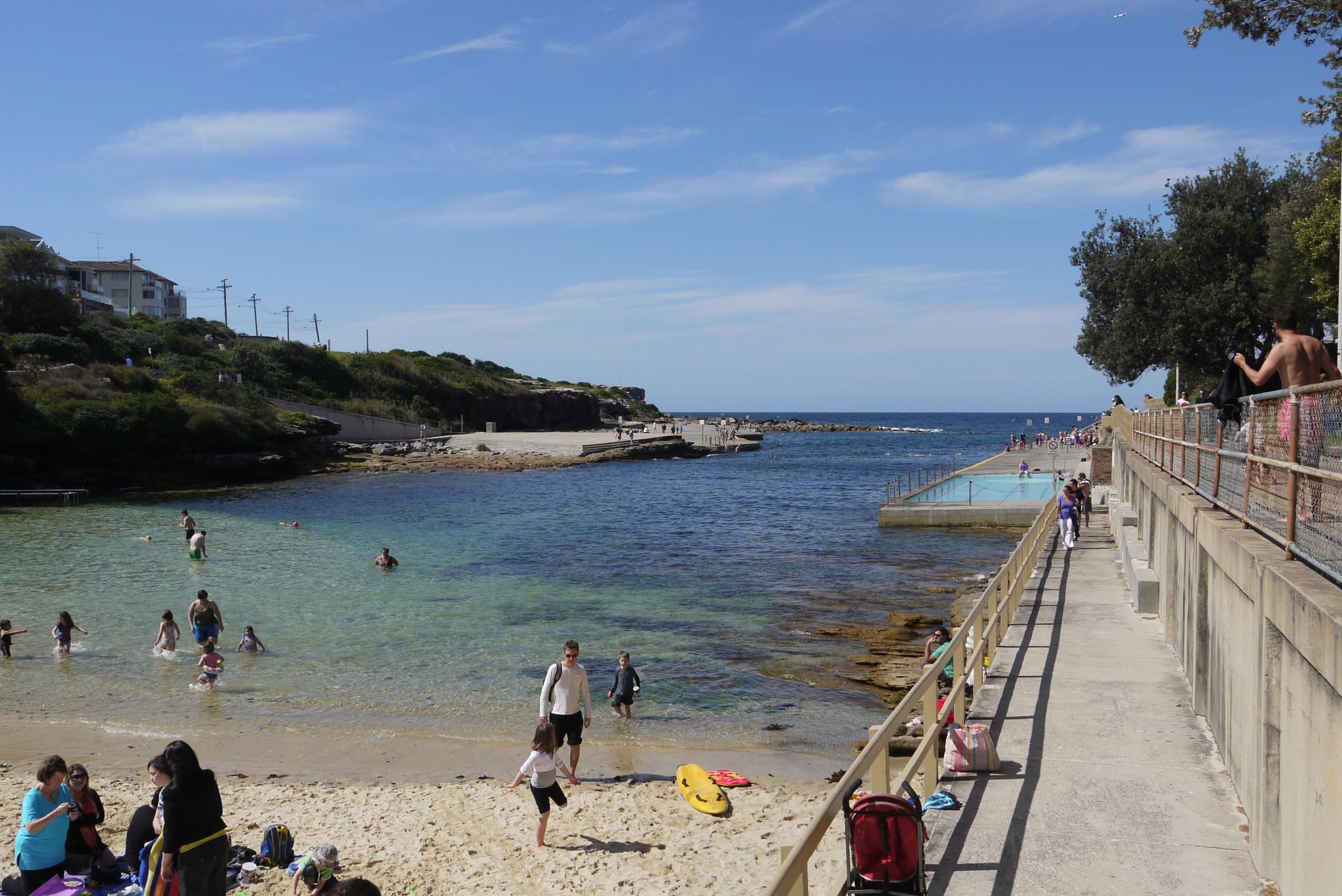 several people are sitting and walking near the water