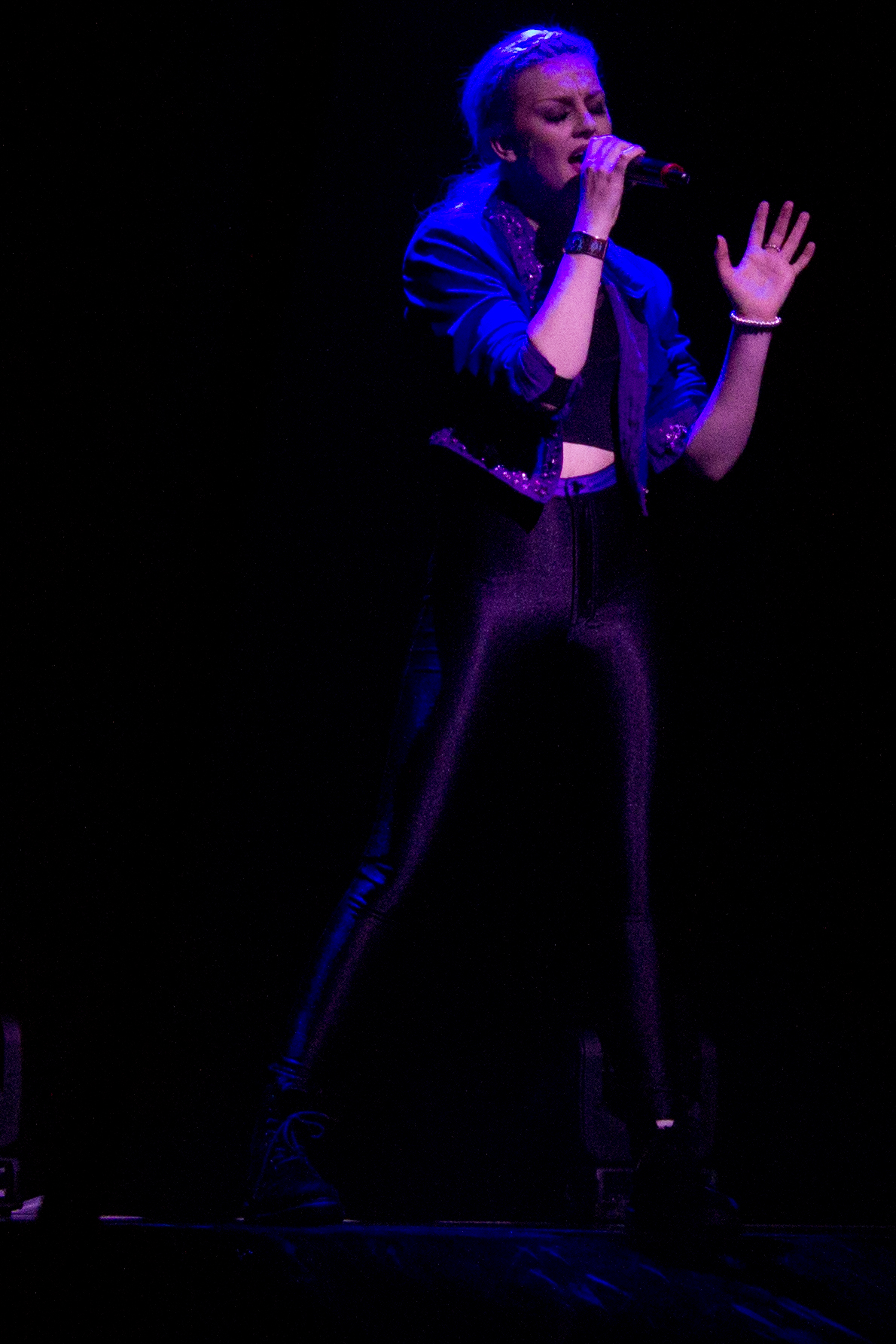 the woman is singing into a microphone with her hand up