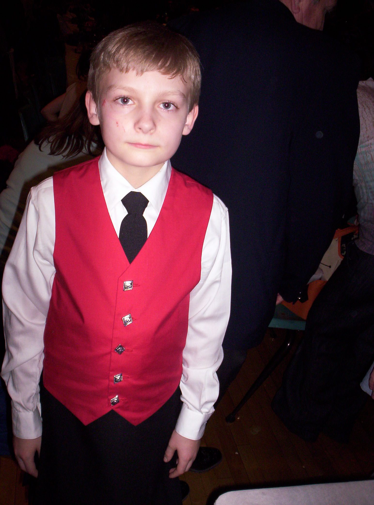 a boy in a red vest and white shirt wearing a tie