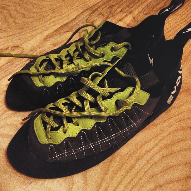a pair of shoes with black, yellow and white laces