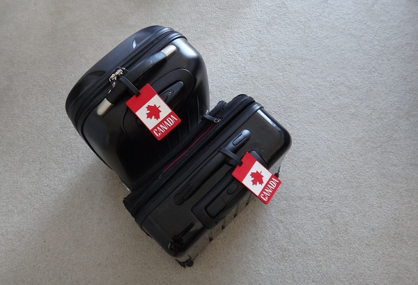 two suitcases on carpet with canadian stickers in them
