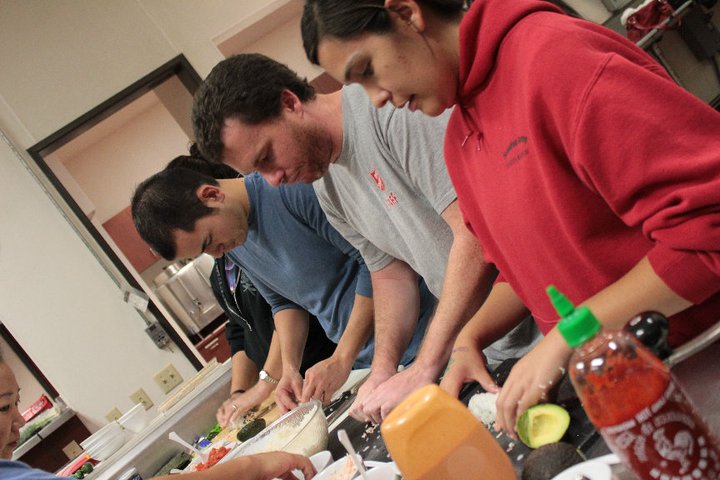 several people are working in a kitchen with food