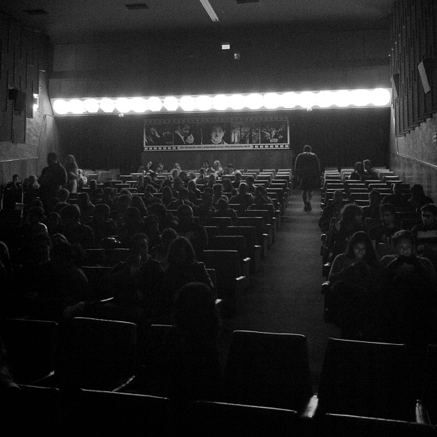 people in seats at an auditorium with a microphone