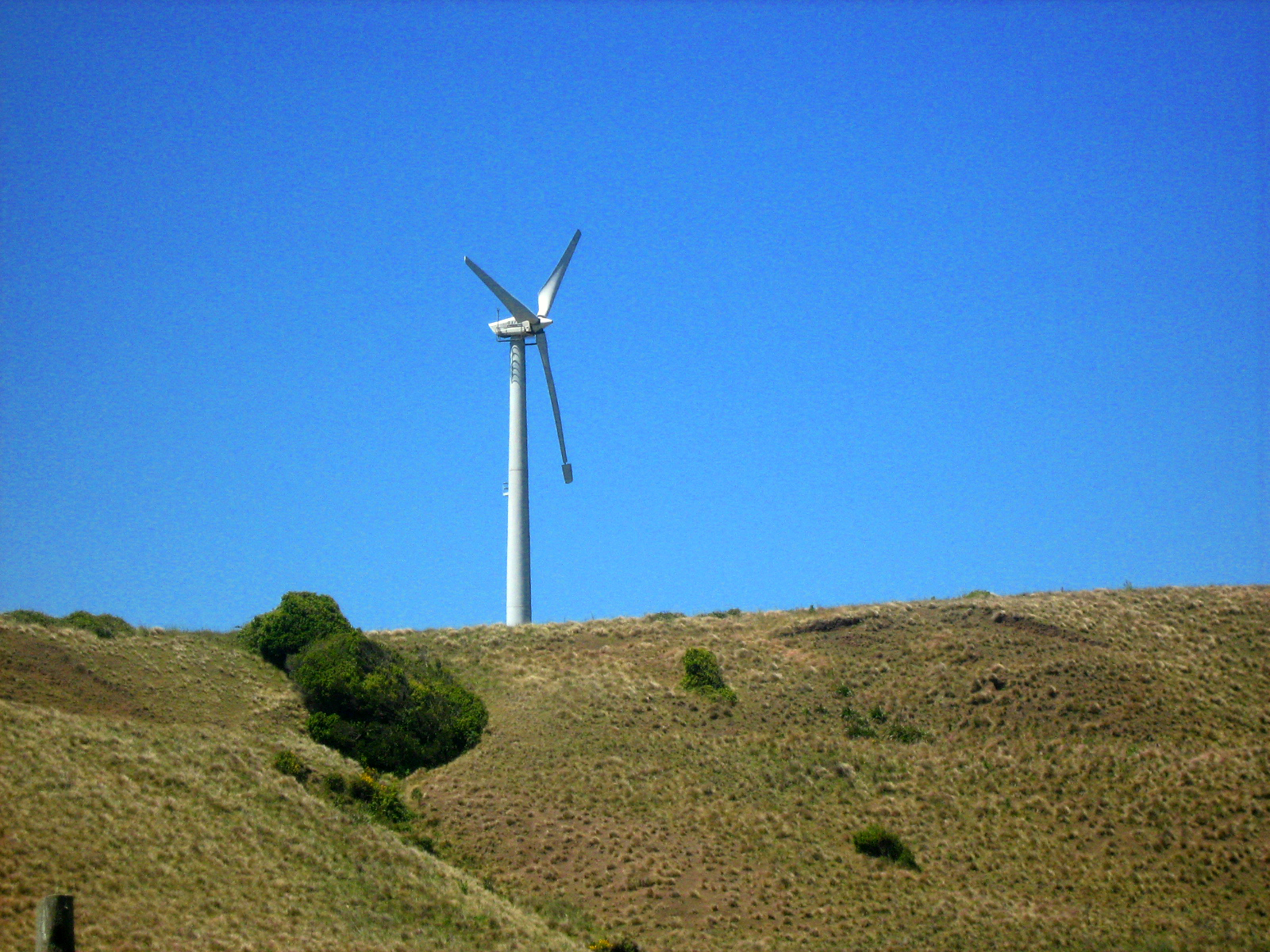 a single windmill stands on top of a hillside