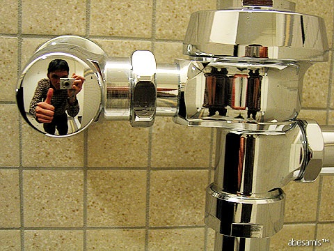 someone takes a po of their reflection in the mirror of a faucet