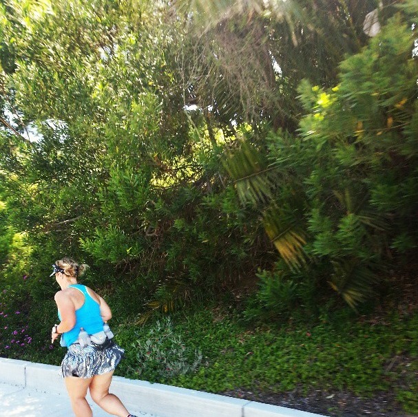 a woman running on a white wall along side some trees