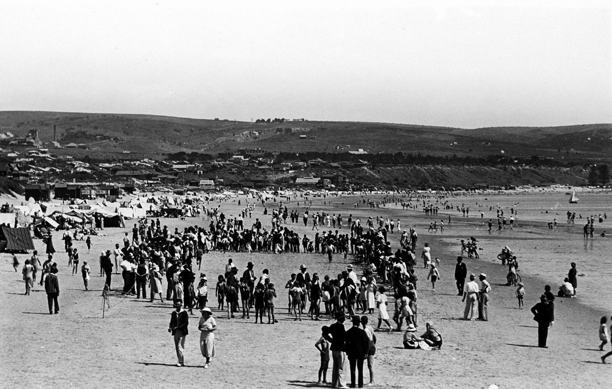 many people are walking in the sand near mountains