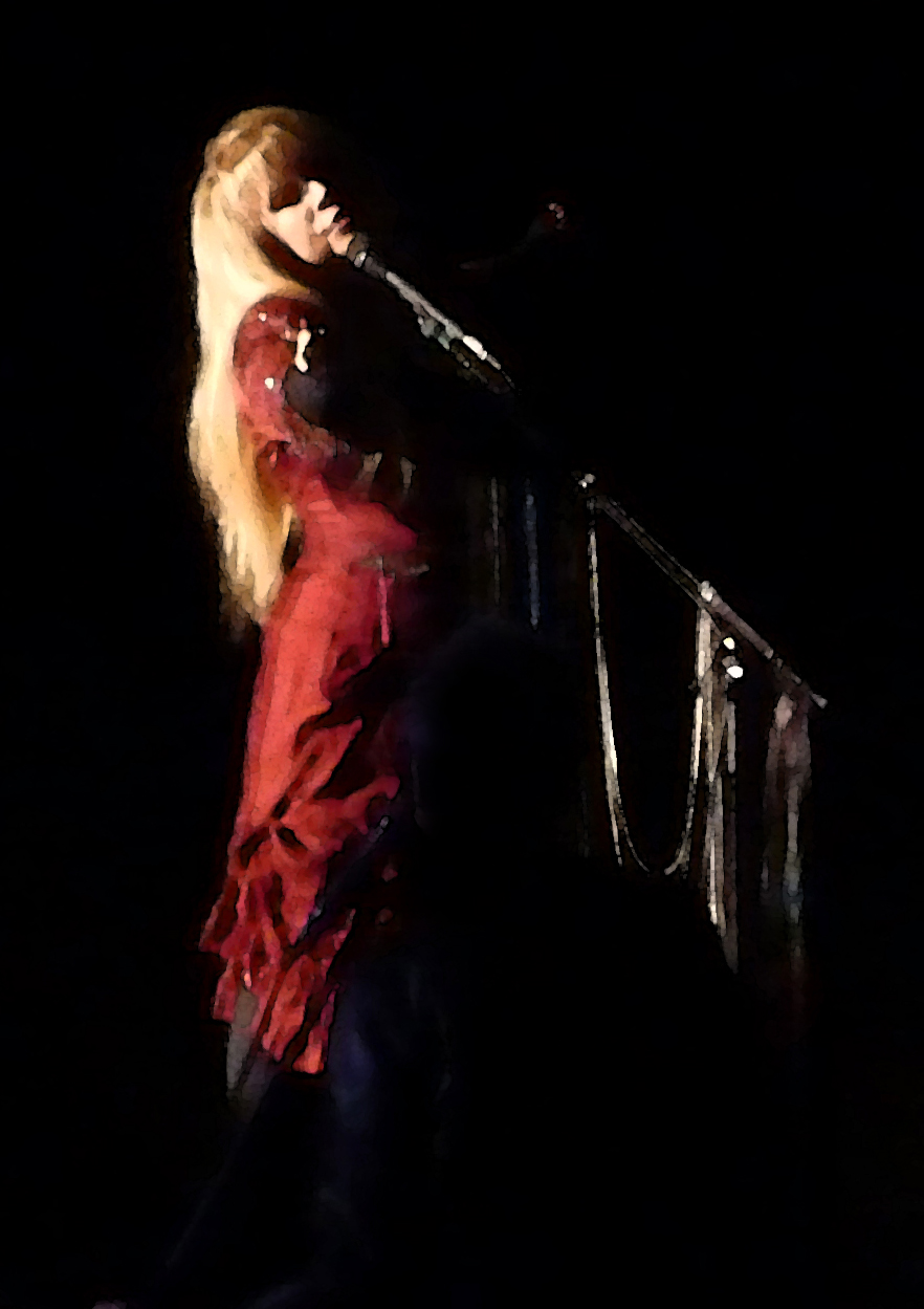 a blond woman with red shirt and long hair on stage