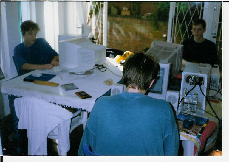 three men sitting at a table looking at soing