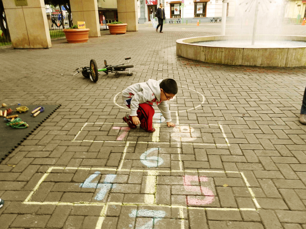 child looking down at floor design in brick paved area