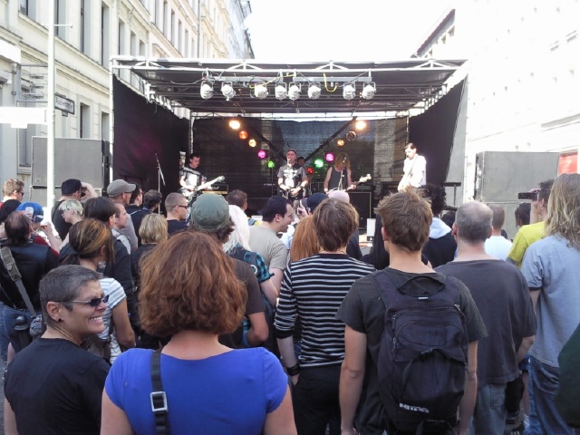 group of people on a crowded street watching a band