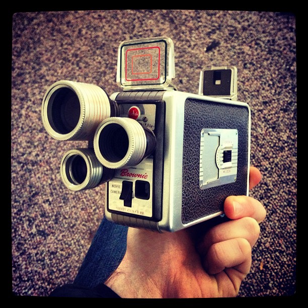 a hand holding an old camera with some small cameras on it